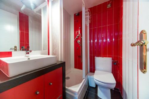 baño rojo con lavabo blanco y aseo en CHUECA Apartamentos, en Madrid