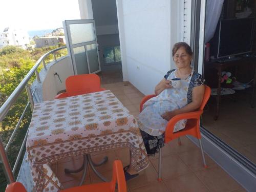 a woman sitting at a table with a cup of coffee at Villa Selmani in Ksamil