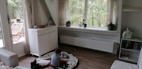 a child sitting on a bean bag in a room with windows at L'évasion - Bungalow 102 in Durbuy
