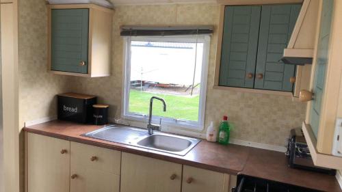 cocina con fregadero y ventana en Esmeralda's Caravan Hire Mablethorpe en Mablethorpe
