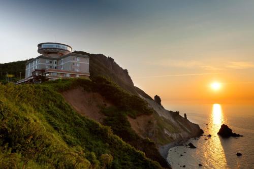 a building on a hill next to the ocean at sunset at Hotel Neu Schloss Otaru in Otaru