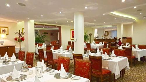 a restaurant with tables and chairs with white tablecloths at Hotel Amaryllis in Swarzędz