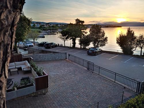 een parkeerplaats met auto's geparkeerd naast een waterlichaam bij apartman Emili in Malinska