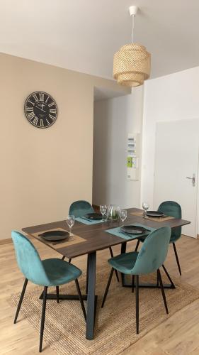 a dining room table with chairs and a clock on the wall at Appartement chaleureux in Boulogne-sur-Mer