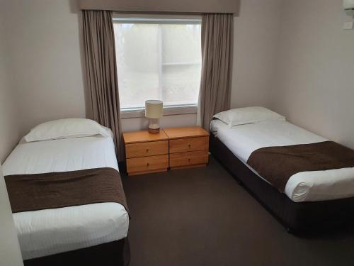 two beds in a room with a window at The Aston Motel Tamworth in Tamworth