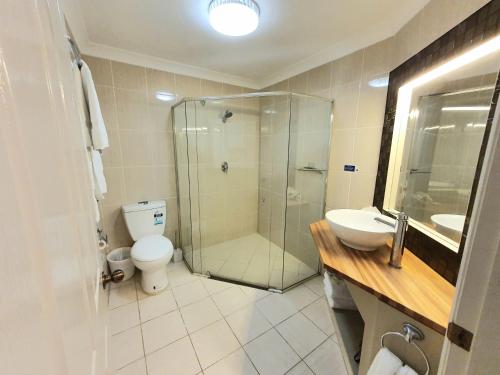 a bathroom with a shower and a toilet and a sink at The Aston Motel Tamworth in Tamworth