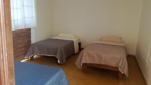Habitación con 2 camas, mesa y ventana en Casa Gaby en Morelia