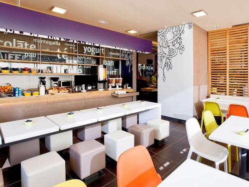 a restaurant with white tables and colorful chairs at Ibis Budget Madrid Getafe in Getafe