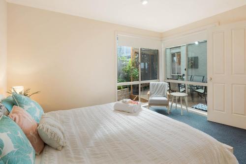 1 dormitorio con cama blanca y balcón en Pelican Lake Holiday House, en Merimbula