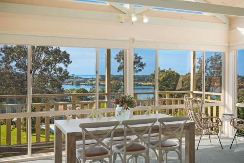 a dining room with a table and chairs on a porch at Pelican Lake Holiday House in Merimbula
