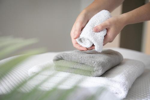 une personne qui essuie une pile de serviettes sur un lit dans l'établissement Design Central Apartment, à Bergame