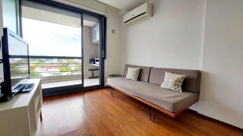 a living room with a couch and a large window at 1 dormitorio - zona Pichincha - Nuevo in Rosario