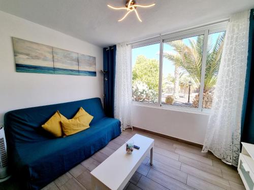 een blauwe bank in een woonkamer met een groot raam bij Apartamento DINO 10 PLAYA ROCA in Costa Teguise