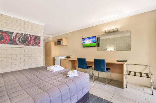 a room with a bed and a desk with two chairs at Stagecoach Inn Motel in Tamworth