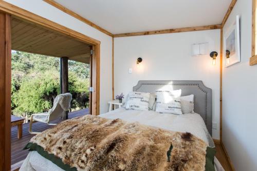 sypialnia z łóżkiem i dużym oknem w obiekcie The Kanuka Cabin w mieście Wanaka