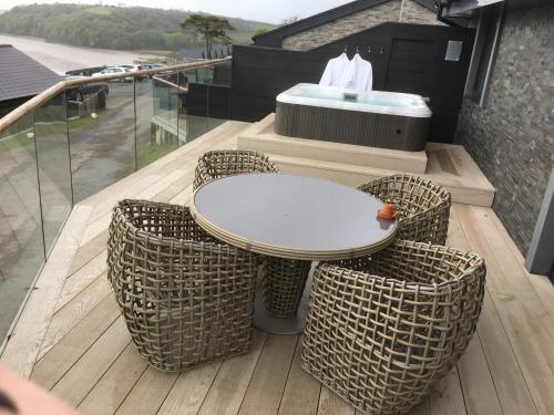 einen Tisch und Stühle auf einem Balkon mit Badewanne in der Unterkunft 5 Luxury Lodge with beautiful views of the Taf Estuary in Carmarthen