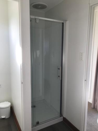 a glass shower stall in a white room at Tophouse Mountainview Cottages in Saint Arnaud