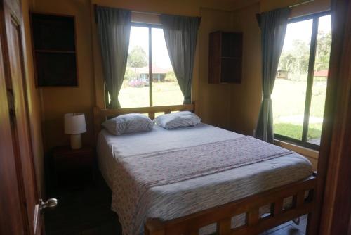 a bedroom with a bed and two windows at Casitas Joys & Leo - Tucan in Santa Rita