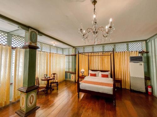 a bedroom with a bed and a chandelier at Las Casas Filipinas de Acuzar in Bagac