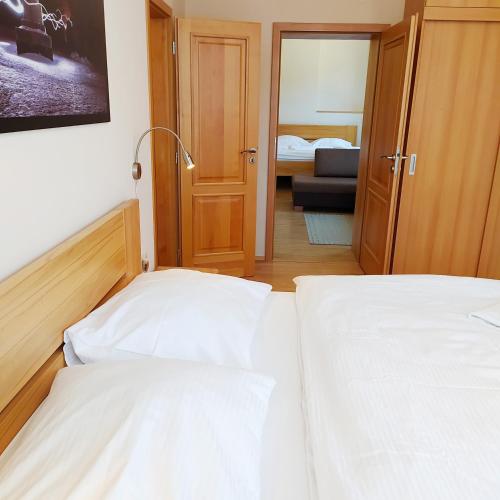 two white beds in a room with a bedroom at Penzion Adéla in Rožnov pod Radhoštěm