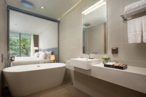 a bathroom with a tub and a sink and a bed at Flamingo Cat Ba Resort Apartment in Hai Phong