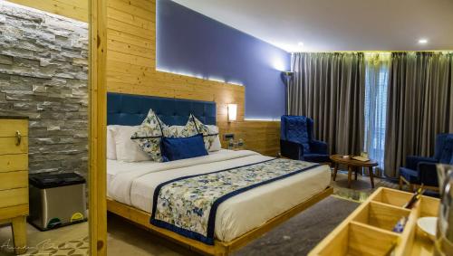 a bedroom with a king sized bed and blue chairs at The Fern Brentwood Resort, Mussoorie in Mussoorie