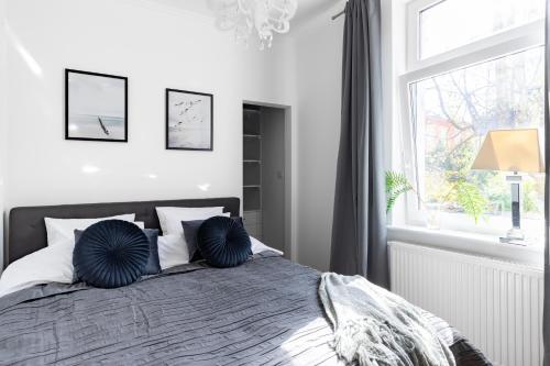 ein Schlafzimmer mit einem Bett mit blauen Kissen und einem Fenster in der Unterkunft Parkowa 33 Apartment Sopot in Sopot