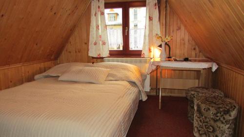Schlafzimmer mit einem Bett, einem Tisch und einem Fenster in der Unterkunft Willa Dewajtis in Zakopane