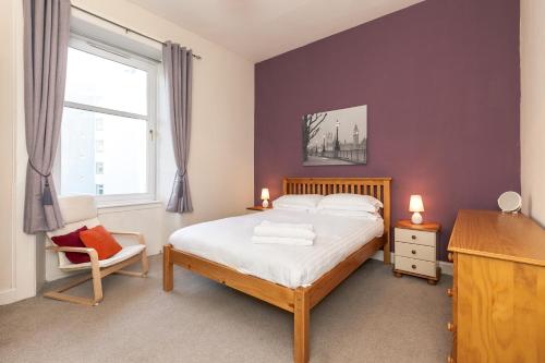 a bedroom with a bed and a chair and a window at The Edinburgh Victorian - 3 Bedroom Apartment in Edinburgh
