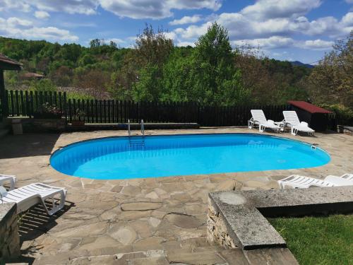 a swimming pool with two chairs and a table and chairs at АРНАТА КЪЩА in Yakovtsi
