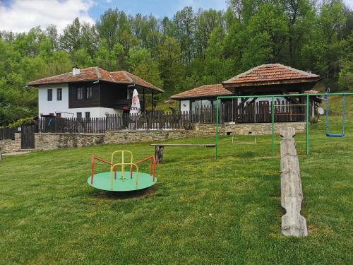 um parque infantil num quintal ao lado de uma casa em АРНАТА КЪЩА em Yakovtsi