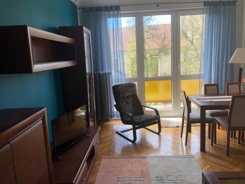 uma sala de estar com uma cadeira e uma sala de jantar em Apartament Roma Gizycko em Giżycko