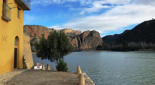 a building next to a body of water with mountains at Lo Raconet in Sant Llorenç de Montgai
