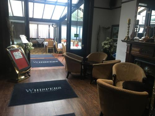 a waiting room with chairs and a table and windows at Harefield Manor Hotel in Romford