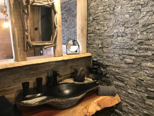 a bathroom with a black sink and a stone wall at Chambres du Gozzi in Afa