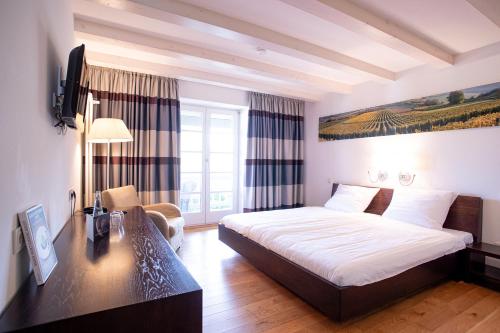 エフリンゲン・キルヒェンにあるTraube Blansingenのベッドとデスクが備わるホテルルームです。