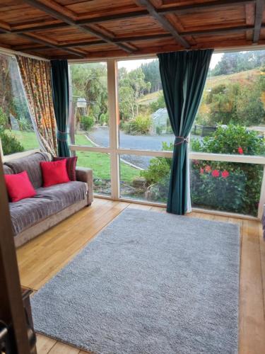 a living room with a couch and a large window at Catlins Lake Sanctuary in Owaka