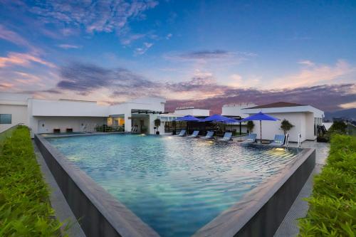 einem Pool mit blauen Sonnenschirmen vor einem Gebäude in der Unterkunft Lemon Tree Premier, Vijayawada in Vijayawāda