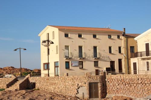 a building in front of a stone wall at Miramare Isola Rossa in Isola Rossa