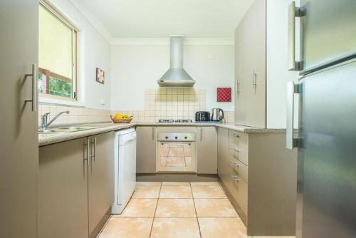 a kitchen with white cabinets and a stainless steel refrigerator at Island Time Villas in Titikaweka