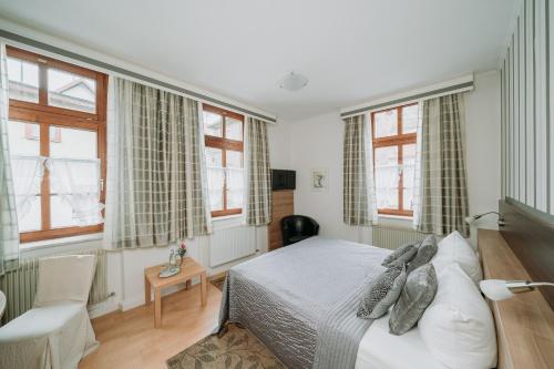 a bedroom with a bed in a room with windows at Fränkischer Gasthof-Hotel zum Koppen in Gemünden