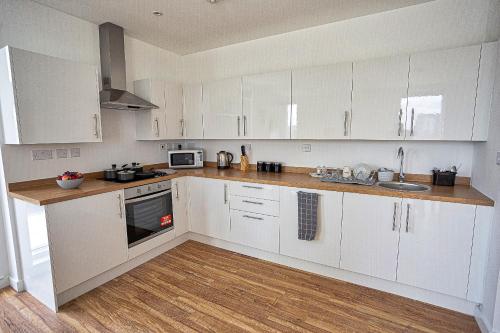 a kitchen with white cabinets and a wooden floor at Gillingham One in Gillingham