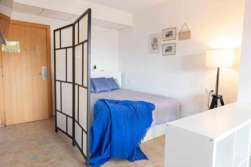 Un dormitorio con una cama con una manta azul. en Apartamento junto a la playa con piscina y parking en Punta Umbría