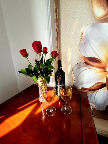 a table with two glasses of wine and a vase of roses at Little Saigon Hotel in Chau Doc
