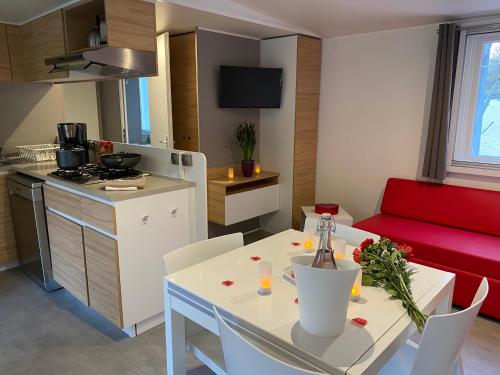 Il comprend une cuisine et un salon avec une table blanche et un canapé rouge. dans l'établissement Les Cottages du Herisson, à Bonlieu