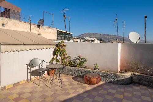 un patio con mesa, sillas y pared en Riad Malak, en Fez