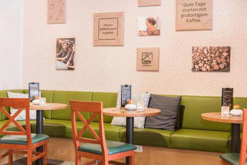 a restaurant with two tables and a green couch at JUFA Hotel Grundlsee in Grundlsee