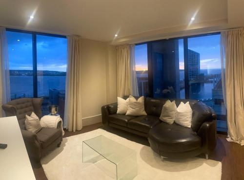 a living room with a leather couch and a large window at NOVU Apartments Liverpool Waterfront in Liverpool