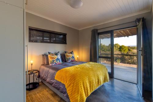 1 dormitorio con 1 cama y puerta corredera de cristal en Steenbok farm cottages -Mongoose cottage en Wolseley