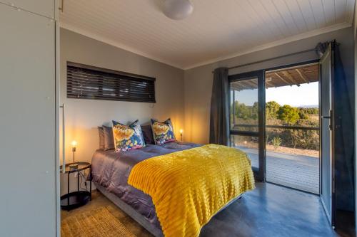 a bedroom with a bed and a sliding glass door at Steenbok farm cottages -Mongoose cottage in Wolseley